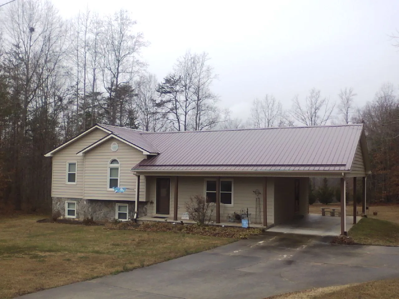 Burgundy metal roof on a tan split level home with an attached carport in Easton