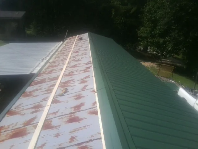 Old rusted panels beside newly installed green metal roofing — Wind Damage Roof Repair by Roofing Brothers in Easton